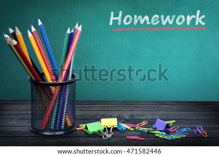 Homework text on green board and group of pencils