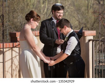 Homosexual Couple Holding Hands With Rabbi Officiating