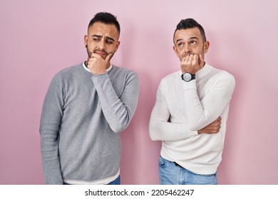 Homosexual Couple Standing Over Pink Background Thinking Worried About A Question, Concerned And Nervous With Hand On Chin 