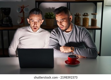 Homosexual Couple Using Computer Laptop In Shock Face, Looking Skeptical And Sarcastic, Surprised With Open Mouth 