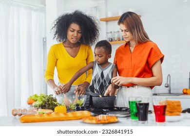 Homosexual family teaches black son to happily cook in the kitchen to prepare dinner. LGBT family lifestyle - Powered by Shutterstock