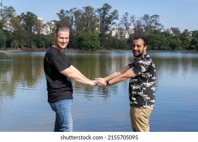 Homosexual Mature White Male Couple Holding Hands Smiling At A Lake