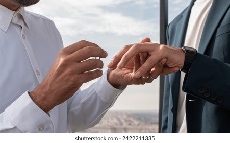 Homosexual men getting married outdoors, on a Madrid terrace overlooking the city, after the civil ceremony. They put on their wedding ring. - Powered by Shutterstock