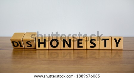 Honesty or dishonesty symbol. Turned cube and changed the word 'dishonesty' to 'honesty'. Beautiful wooden table, white background. Business and honesty or dishonesty concept. Copy space.