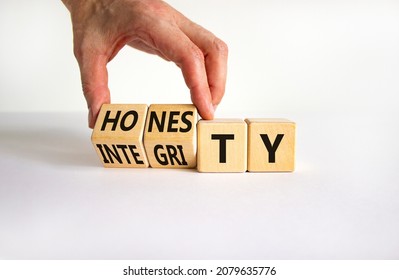 Honesty and integrity symbol. Businessman turns wooden cubes and changes the word integrity to honesty. Beautiful white table, white background, copy space. Business and honesty and integrity concept.