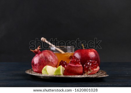Honey, apples and pomegranate on dark blue wooden table. Rosh Hashanah holiday