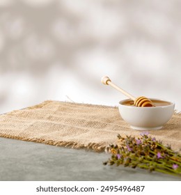 Honey with honey dipper in white bowl with lavender and canvas jute kitchencloth on stone marble table and white wall with natural sunlight background copy space for products. - Powered by Shutterstock