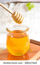 Honey drip in jar on the table. Old board background