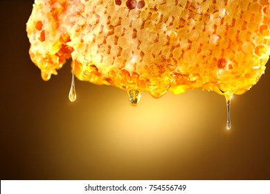 Honey dripping from honey comb on yellow background. Thick honey dipping from the honeycomb. Healthy food concept, diet, dieting
