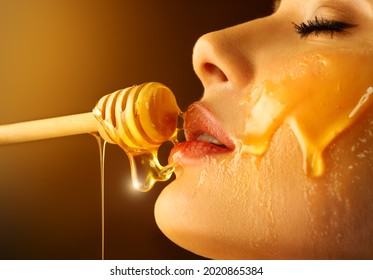Honey dripping from honey dipper on sexy girl lips. Thick honey dipping from the wooden honey spoon. Beauty model woman open mouth, model eating nectar. Healthy food concept, diet, dessert