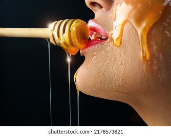 Honey dripping from honey dipper on sexy girl lips. Thick honey dipping from the wooden honey spoon. Beauty model woman open mouth, model eating nectar. Healthy food concept, diet, dessert. 