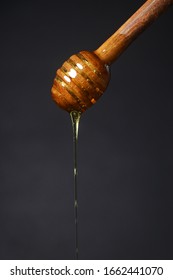 Honey Dripping From Honey Dripper On Dark Background