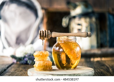 Honey Dripping Over Vax Comb On Wooden Table