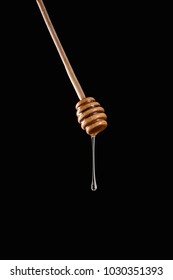 Honey Dripping From Honey Stick Isolated On Black