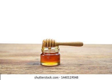 Honey glass bottle with dipper on wood table on white background