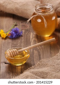 honey in a glass bowl on a wooden boards background and burlap