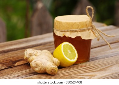 Honey In A Glass Jar, Ginger Root, A Lemon On A Wooden Table In A Summer Sunny Day . Honey With  Ginger And Lemon