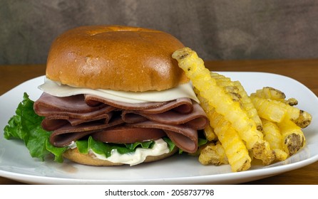 Honey Ham On A Bun Top With Provolone Cheese, And Served With A Side Of Fries