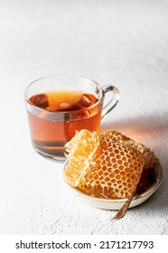 Honey In Honeycomb In Plate With Spoon And Cup Of Tea On A White Background. Vertical Orientation