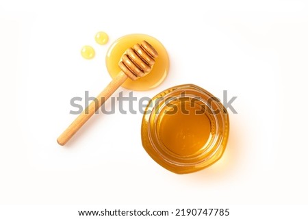 Honey in jar with honey dipper isolated on white background.
