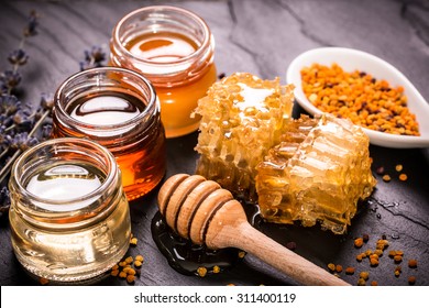 Honey in jar with honey dipper on black stone background 