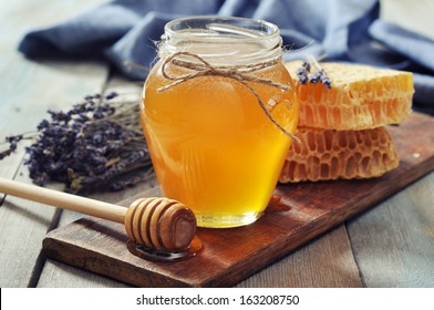 Honey in jar with honey dipper on vintage wooden background 