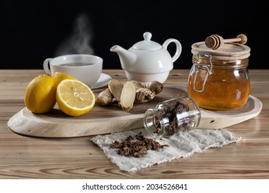 Honey In A Jar, Sliced Lemons And Ginger On A Wooden Rack. Next To It Is Hot Tea In Cups And Cloth With Sprinkled Bee Putty.  Home Treatment For Colds Or Flu. 