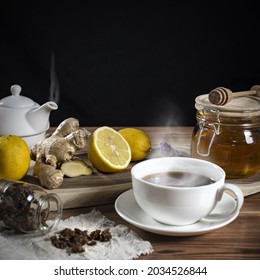 Honey In A Jar, Sliced Lemons And Ginger On A Wooden Rack. Next To It Is Hot Tea In Cups And Cloth With Sprinkled Bee Putty.  Home Treatment For Colds Or Flu. 