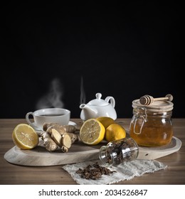 Honey In A Jar, Sliced Lemons And Ginger On A Wooden Rack. Next To It Is Hot Tea In Cups And Cloth With Sprinkled Bee Putty.  Home Treatment For Colds Or Flu. 