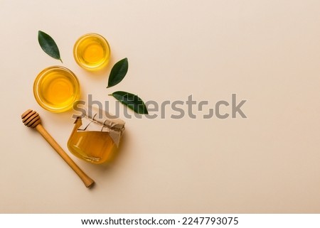 Honey jar with wooden honey dipper on white background top view with copy space. Delicious honey bottle.