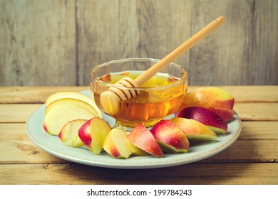 Honey and sliced apple on plate over wooden background for Jewish New Year Rosh Hashahah - Powered by Shutterstock