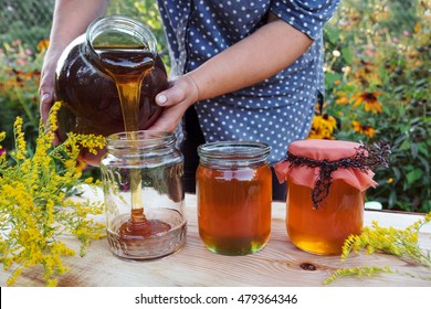 Honey Spill From Glass Jar. Woman Holding Bottle Of Honey.