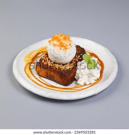 Honey toast with coconut flavour ice cream on top and side. The dessert is on white marble dish on a wooden plate - side view with copy space and white background