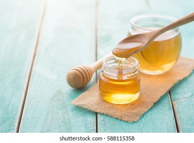 Honey with wooden honey dipper on blue wooden table - Shutterstock ID 588115358