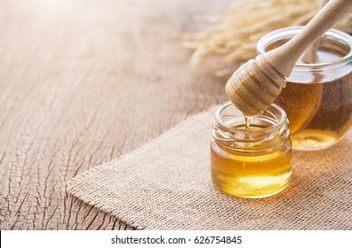 Honey with wooden honey dipper on wooden table