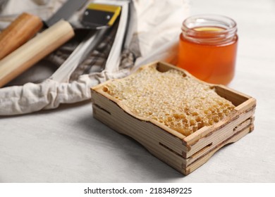 Honeycomb Frame And Beekeeping Tools On White Table