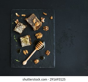 Honeycomb, walnuts and honey dipper on black slate tray over grunge dark backdrop, top view, copy space - Powered by Shutterstock