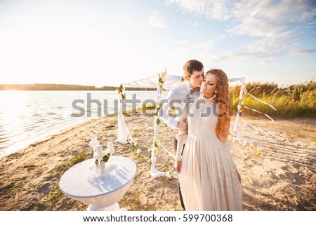 Honeymoon after wedding, couple in love embracing near arch and decorations for wedding ceremony