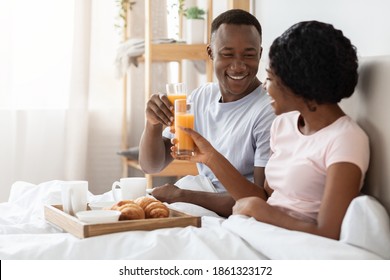 Honeymoon Concept. Happy Black Young Couple Sitting In Bed In Morning And Having Breakfast, Side View, Copy Space. Cheerful African American Man And Woman Enjoying Breakfast In Bed, Talking