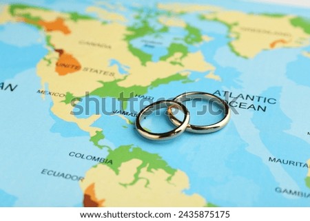 Honeymoon concept. Two golden rings on world map, closeup