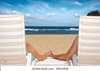 Honeymoon couple in beach chairs holding hands near ocean on reach resort