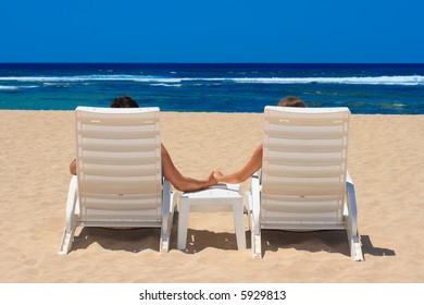 Honeymoon couple in beach chairs on resort sunbathing