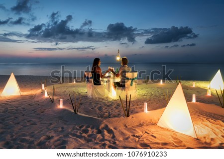 Honeymoon couple is having a private, romantic dinner at a tropical beach