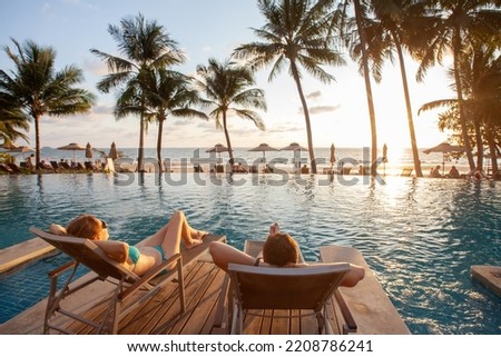 honeymoon couple relaxing in beach hotel near swimming pool at sunset, dream holidays