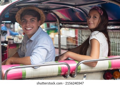Honeymoon traveling couple taking holiday vacation in Thailand, riding Tuktuk motor tricycle