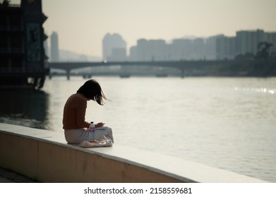 HONG K, HONG KONG - Feb 26, 2022: AA Woman Resting Next To Shing Mun River, Hong Kong At Sunny Day