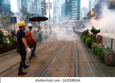 Hong Kong 12th June 2019: Protester using an umbrella to protect from tear gas canisters during clashes with police in the main financial district of Hong Kong. With tear gas filling the air.