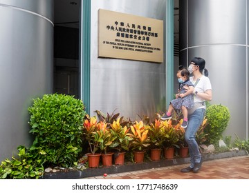 Hong Kong - 8 July 2020: A woman carrier a baby walk past a plaque outside the Office for Safeguarding National Security of the Central People's Government in the Hong Kong. - Shutterstock ID 1771748639