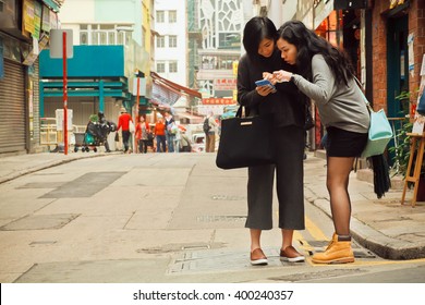 HONG KONG, CHINA - FEB 12: Two Women Watching Cell Phone To Find Way In Big City On February 12, 2016. There Are 1,223 Skyscrapers In Hong Kong.