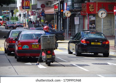 Hong Kong, China - Nov 27, 2016: Red Express Scooter With Old Metal Delivery Box And Taxies Waiting At Red Traffic Light